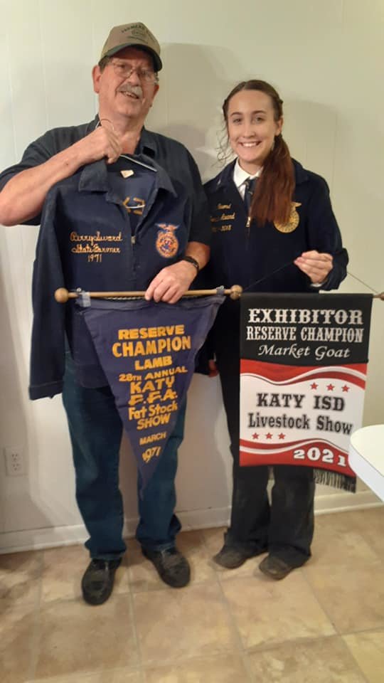 Perry Sword and his granddaughter Erin Sword display their reserve champion banners for the lamb and market goat competitions, respectively. Perry earned his banner in 1971 and passed the FFA tradition down to his children and grandchildren.